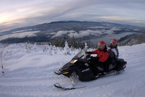 backcountry snowmobiling with a river in the background